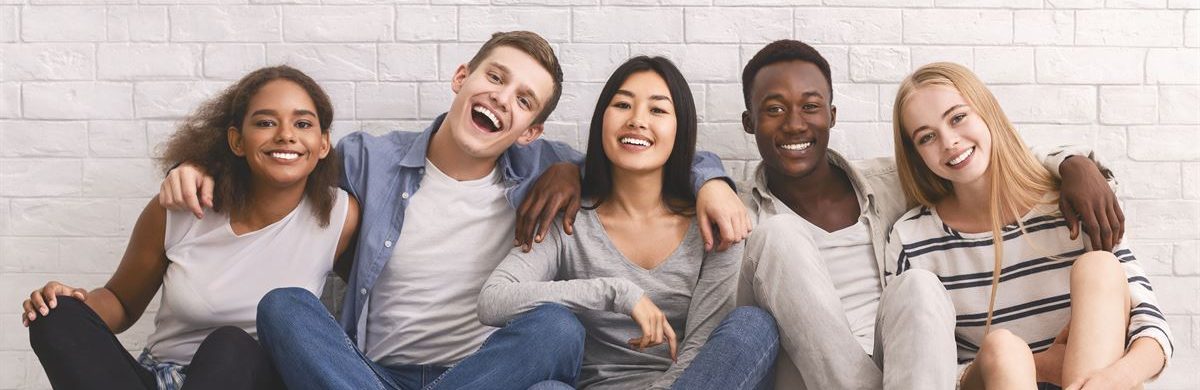 Group of youths sitting on the floor together and smiling.